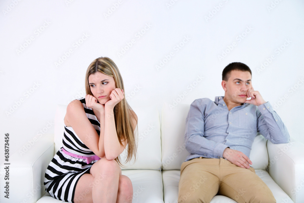 Loving couple sitting on sofa, on light background