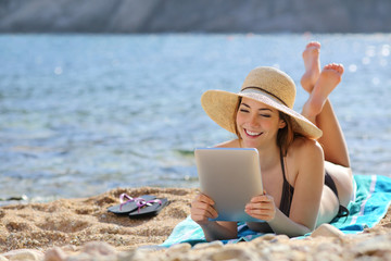 Sticker - Pretty woman reading a tablet reader on the beach on vacations