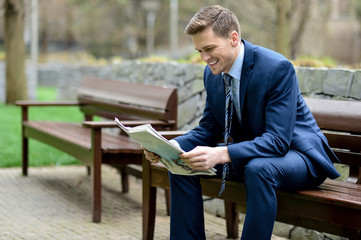 Wall Mural - Smiling businessman reading newspapers in park