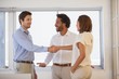 © lightwavemedia - Business people shaking hands besides colleague at office