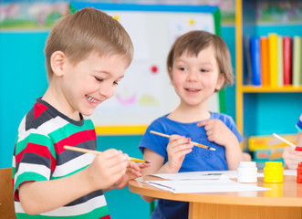 Cute children drawing with colorful paints at kindergarten