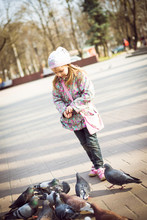 Beautiful Little Girl Feeding Pigeons  In Park