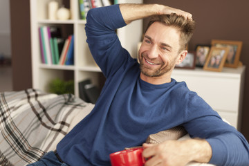 Wall Mural - Handsome man relaxing with cup of coffee at home