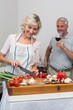 © lightwavemedia - Man with wine glass and woman chopping vegetables in kitchen