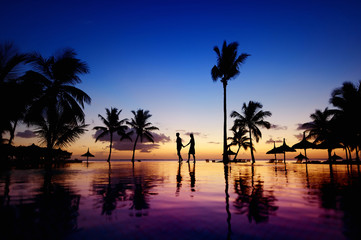 Wall Mural - Silhouettes of young couple at scenic sunset