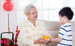 © szeyuen - Asian boy giving mandarin oranges to his grandmother