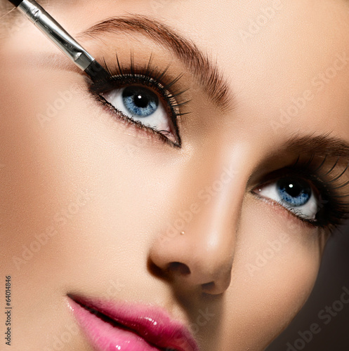 Fototapeta na wymiar Makeup applying closeup. Eyeliner. Cosmetic eyeshadows