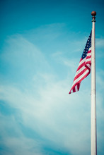 American Flag - Star And Stripes Floating Over A Cloudy Blue Sky