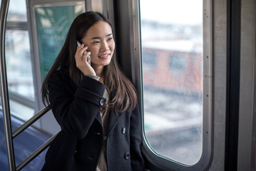 Sticker - Young Asian woman talking cellphone riding train