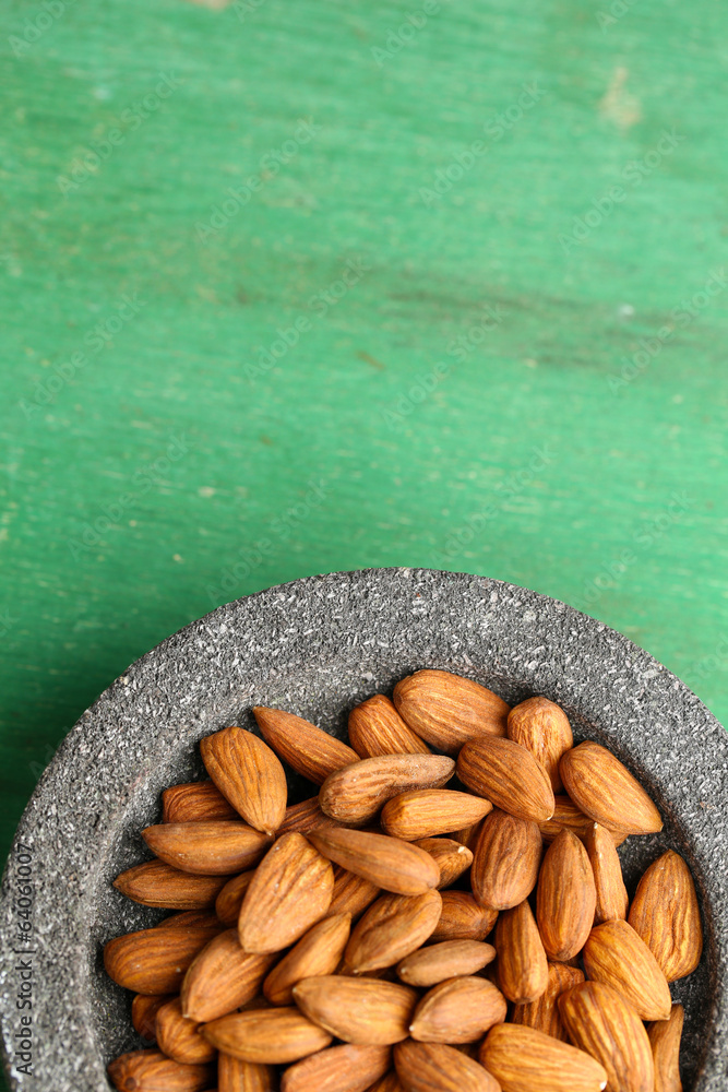 Almonds in bowl on color wooden background
