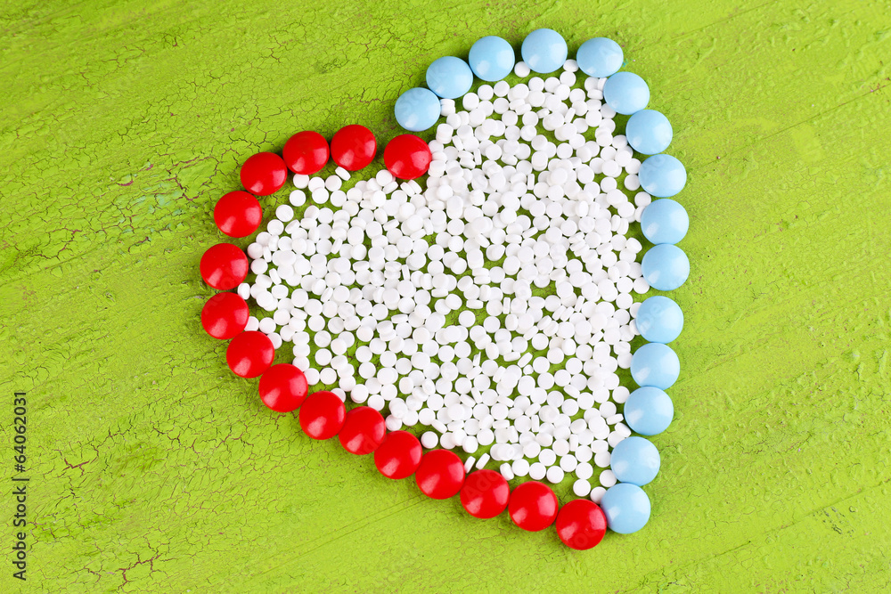Heart of pills on wooden background
