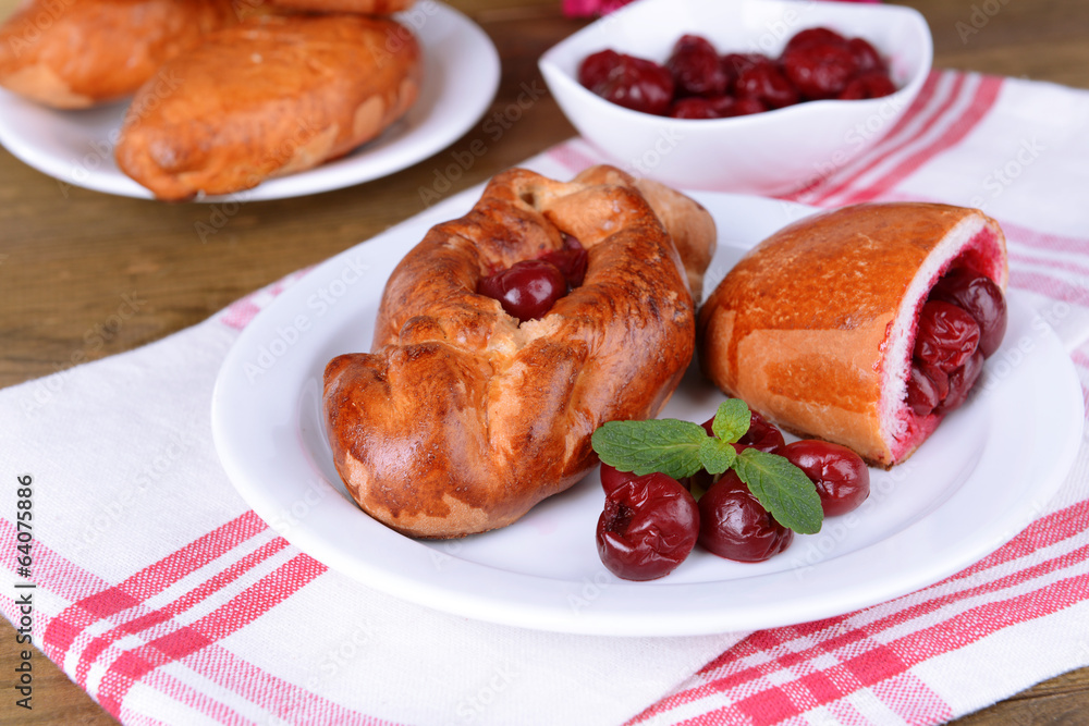 Fresh baked pasties with cherry on plate on table close-up