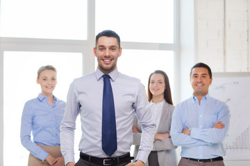 Poster - smiling businessman in office with team on back