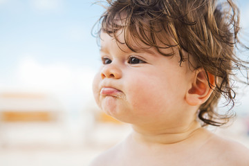 Boy with curly hair on the sunny beach of Mexico.