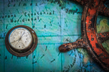 Old vintage barometer together with old ship's wheel attached on a wall