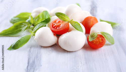 Plakat na papierze fotorealistycznym Smaczny ser mozzarella z bazylią i pomidorami, na drewnianych