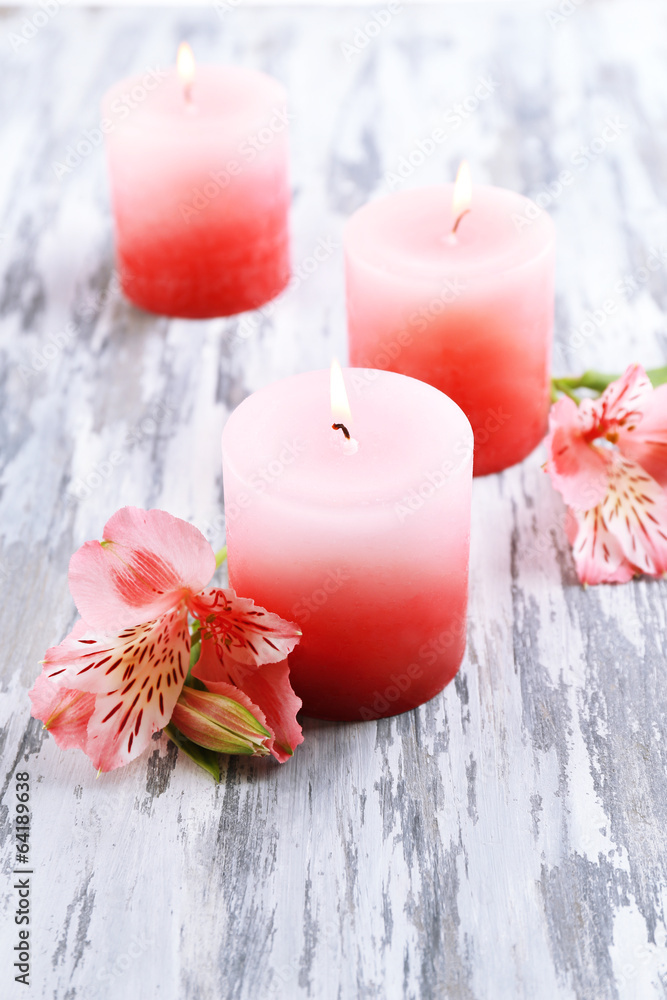 Beautiful candles with flowers on wooden background