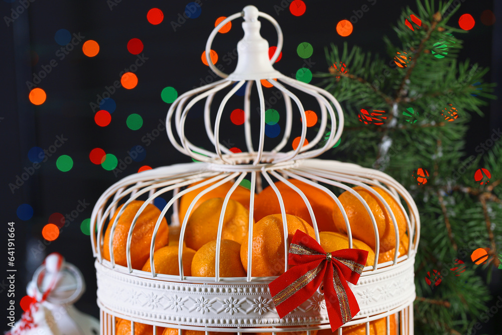 Tangerines in decorative cage with Christmas decor,