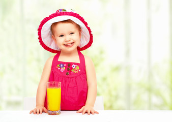 Wall Mural - baby girl drinking orange juice in the summer