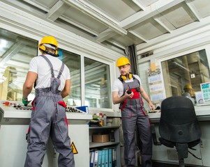 Two operators wearing safety hat in a factory control room