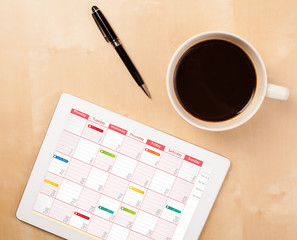 Wall Mural - tablet pc showing calendar on screen with a cup of coffee on a d