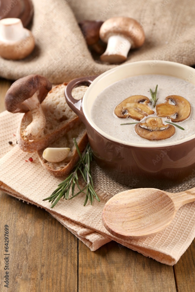 Mushroom soup in pot, on wooden background