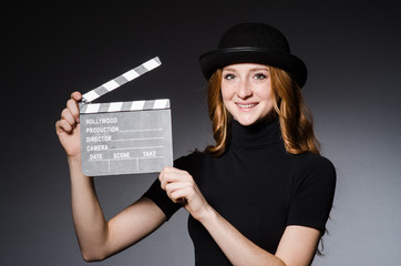 Young redhead girl in hat with movie board against grey backgrou