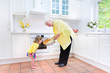 © famveldman - Beautiful grandmother and little girl baking pie in white kitche