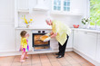 © famveldman - Loving grandmother and little girl baking pie in white kitche