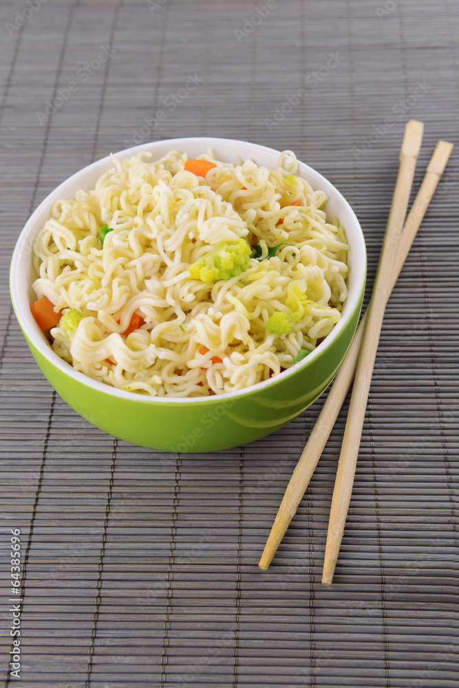 Tasty instant noodles with vegetables in bowl on table close-up