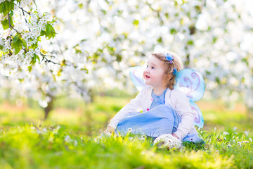 Wall Mural - Adorable toddler girl in fairy costume in fruit apple garden