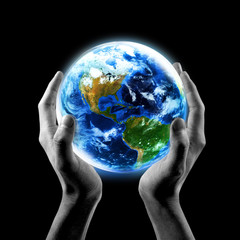 Hands holding Earth with a black background.