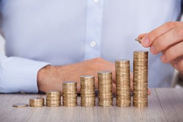 Businessman Stacking Euro Coins At Desk