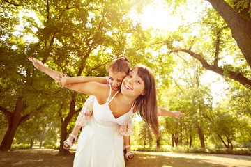 Playful mother and little daughter enjoying in nature.