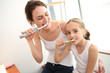 © goodluz - Mother teaching little girl how to brush her teeth