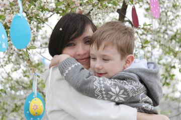 Mother and son in blooming garden decorating for Easter