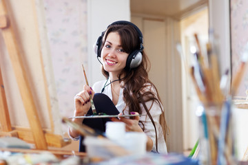 Wall Mural - Female artist in headphones paints picture