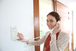 © goodluz - Woman inside home answering security phone