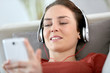 © goodluz - Woman relaxing in sofa with headphones on