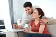 © goodluz - Couple at home shopping online with laptop