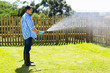 young man watering backyard lawn