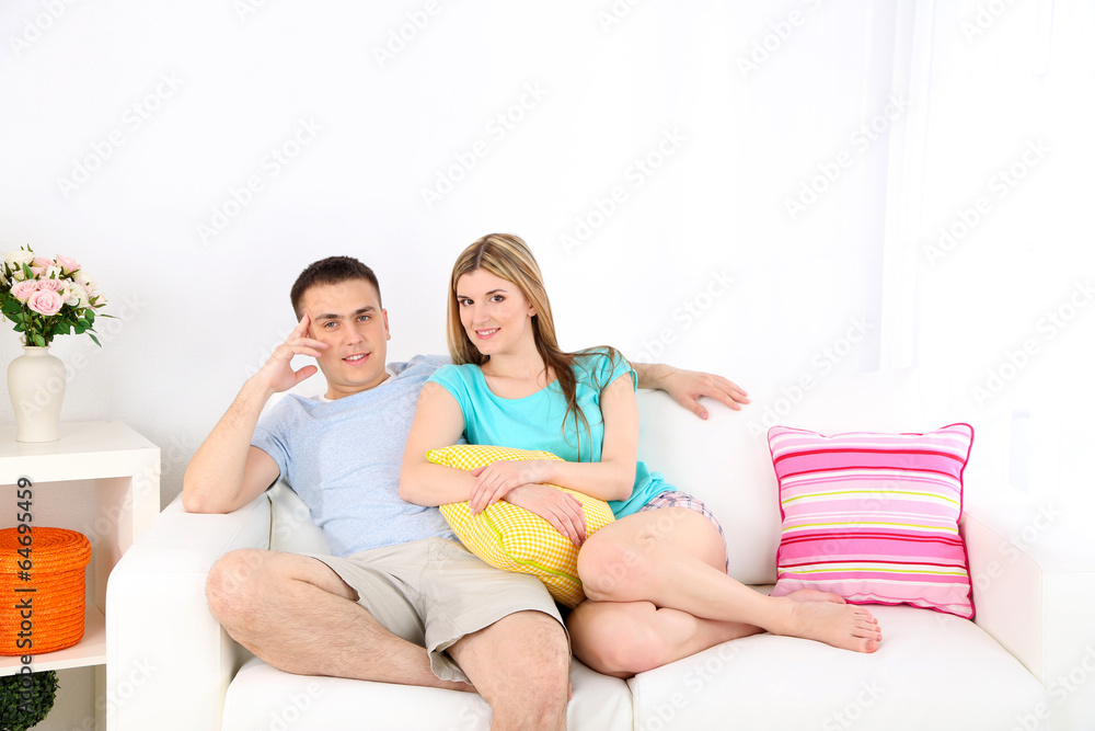 Loving couple sitting on sofa, on home interior background