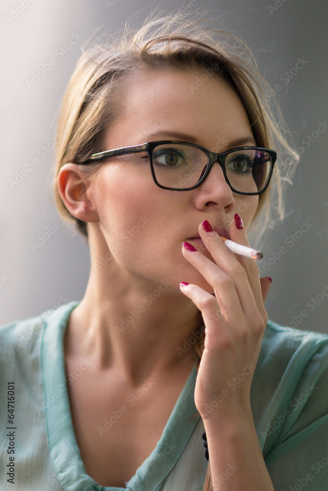 blonde woman smoking cigarette Young blonde woman smoking a cigarette outdoors. Stock Photo