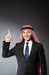 Arab businessman pressing virtual buttons against grey backgroun