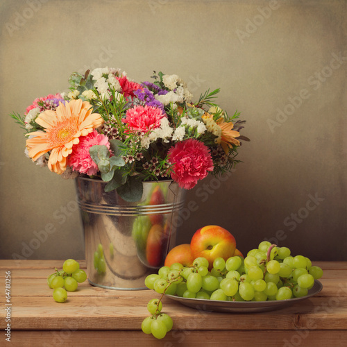 Fototapeta do kuchni Flower bouquet in bucket and fresh fruits on wooden table