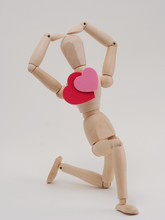 Wooden Figures Kneels On One Leg And Shows The Pose About Love.