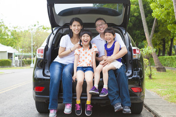 Wall Mural - happy family sitting in the car and their house behind