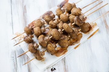 Wall Mural - Baked champignons kebabs, wooden background, high angle view