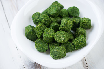 Wall Mural - Glass plate with chopped frozen spinach in a cube shape