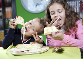 happy little girl and boy eat pizza